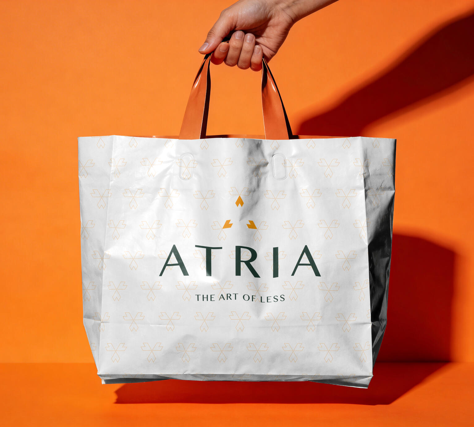 Konzeptdesign für die Papiertragetasche einer fiktiven Premium-Lifestyle-Marke mit Wortmarke, goldenem Musterdruck und Claim The Art of Less
